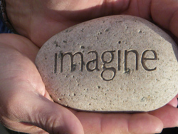 The word IMAGINE is etched into a smooth round stone