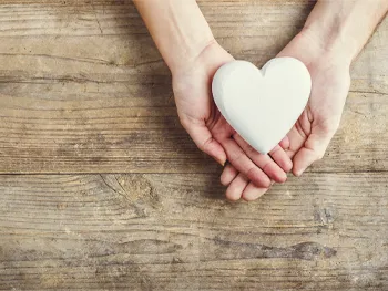 Hands holding a white heart shaped object
