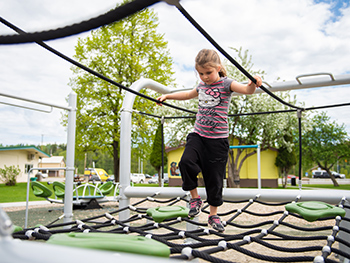 Young girl playing on rope net in playground at at Le Bourdais Park in Quesnel, BC.