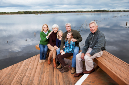 Generational family sitting on a dock by a lake